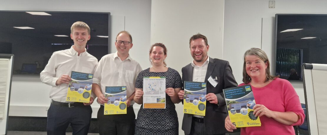 Photo of five people smiling and holding event flyers